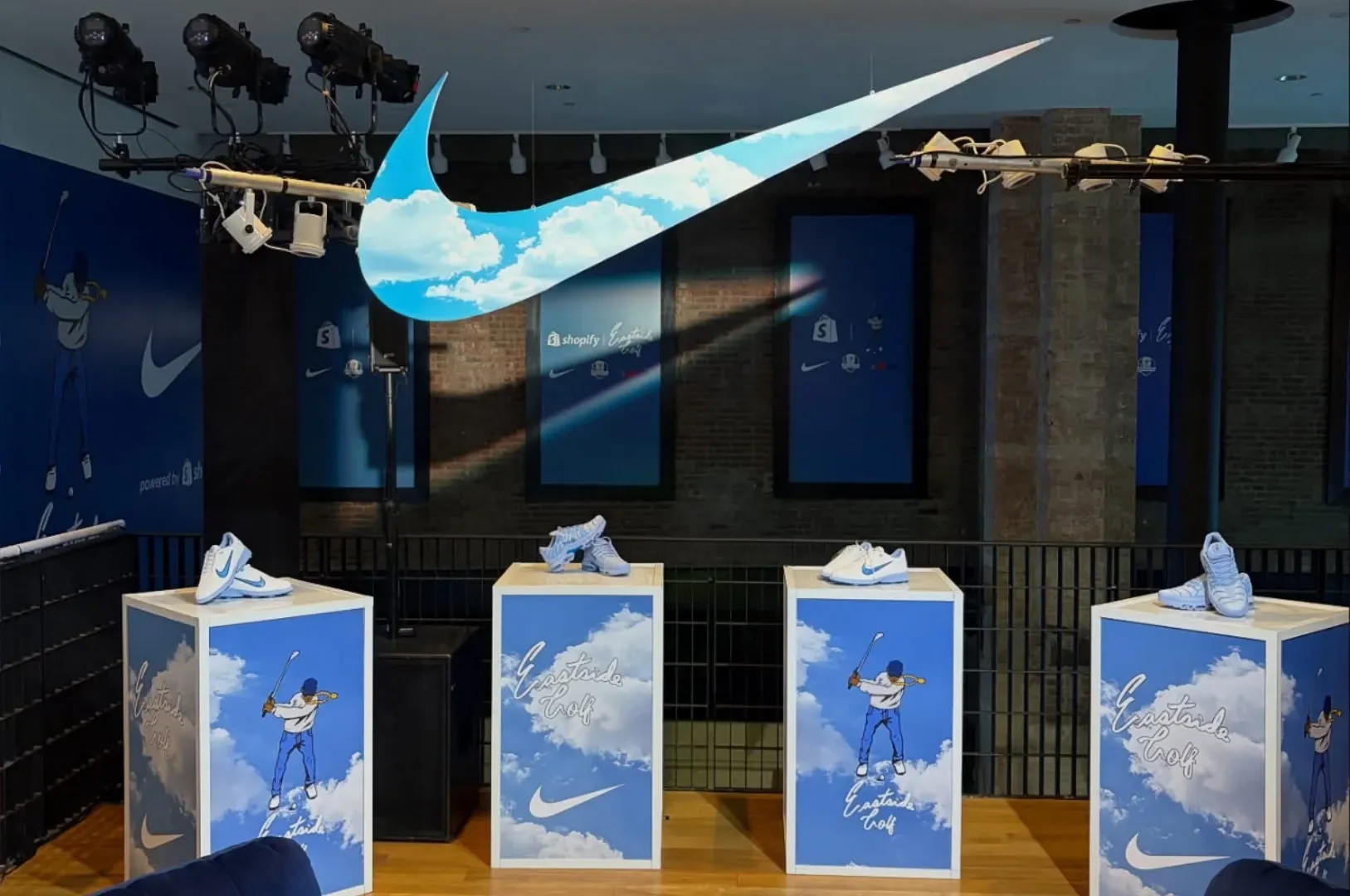 Nike showcase: sky-print plinths under a giant cloud swoosh