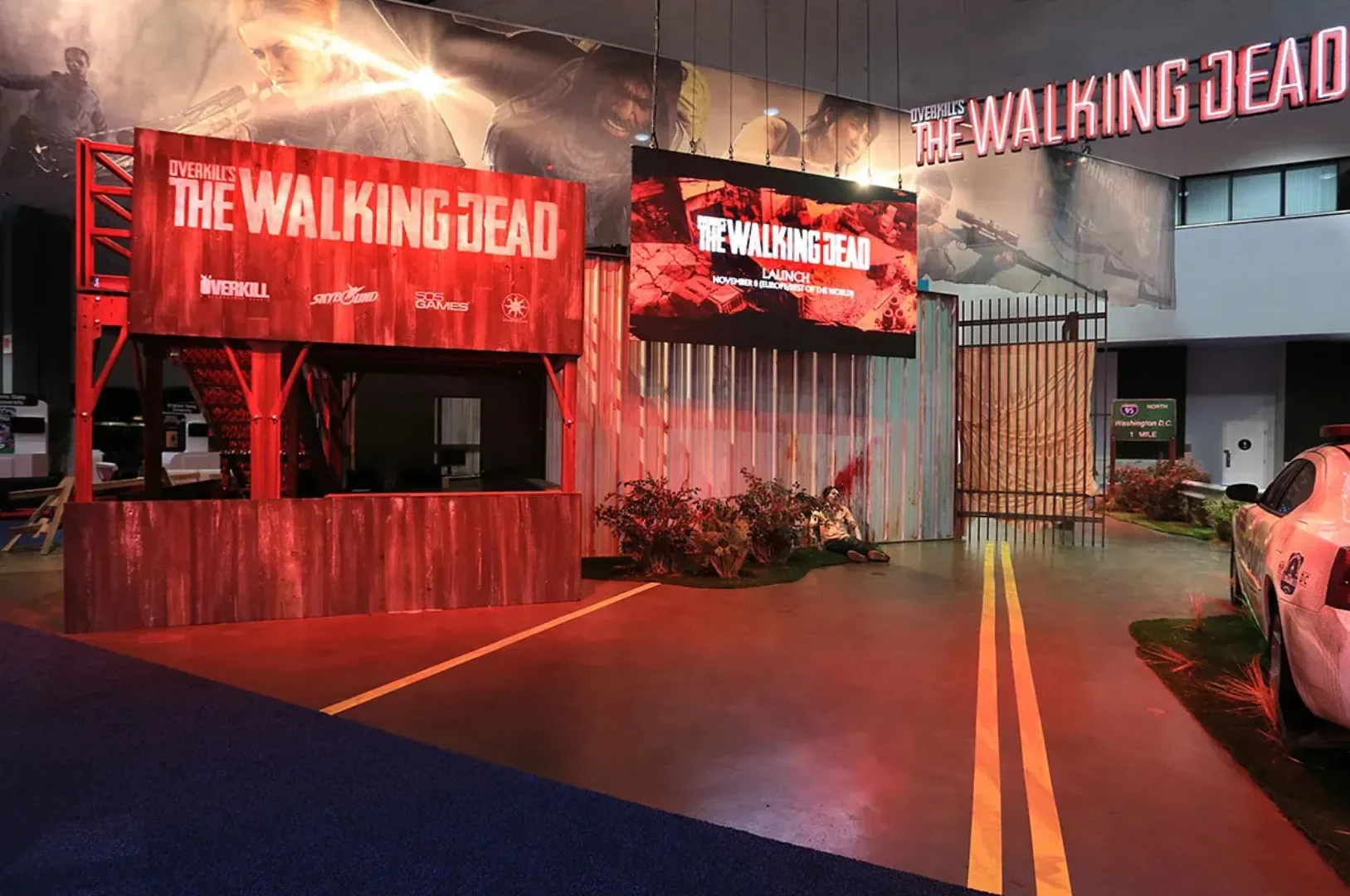The Walking Dead booth: red shipping containers, wrecked cars and a road painted across the floor